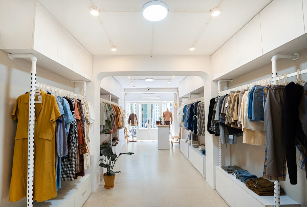 Interior of a modern, minimalist clothing boutique featuring organized racks of apparel, bright lighting, and a welcoming store layout, representing successful retail design.